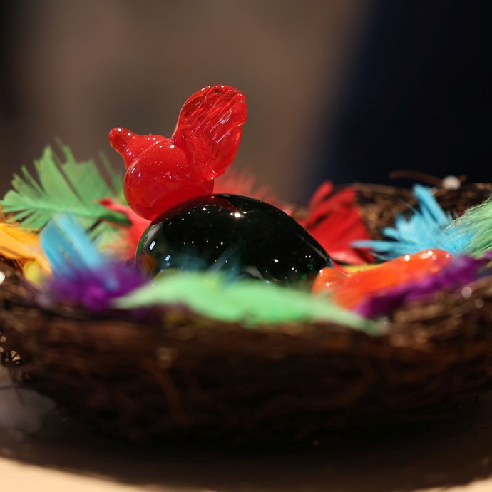Rotgrüner Vogel aus Glas in einem gebastelten Nest (vergrößerte Bildansicht wird geöffnet)