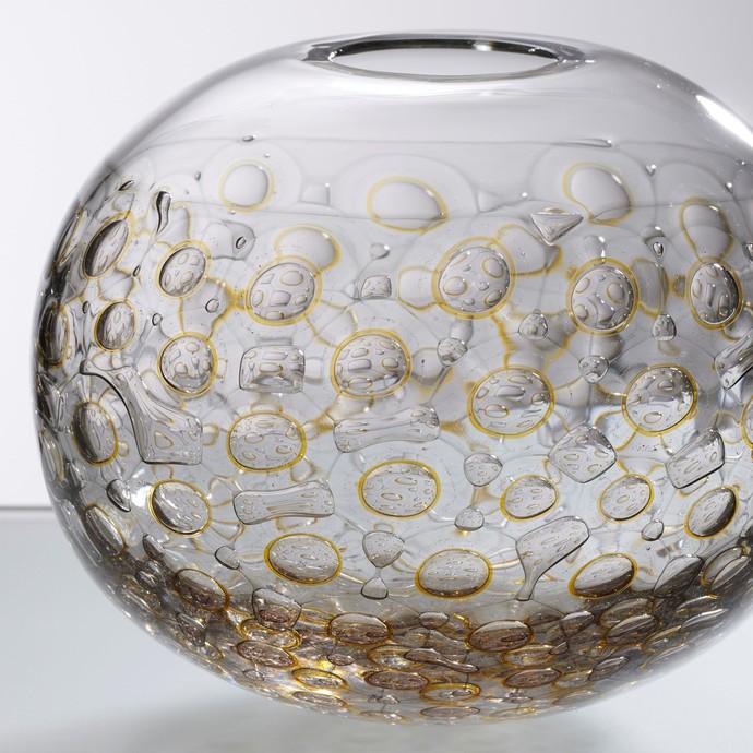 "y·s·g" von Veronika Beckh. Kugel als Glasobjekt mit kleiner Öffnung am oberen Rand und gelblich runden Einfassungen im Glas. (vergrößerte Bildansicht wird geöffnet)