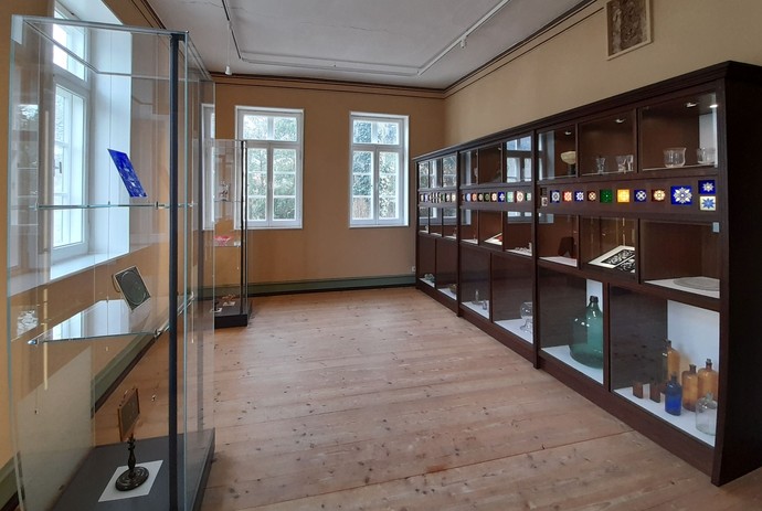 Blick in einen Raum der Dauerausstellung. Links und rechts im Bild Vitrinen mit Gläsern und anderen Objekten.