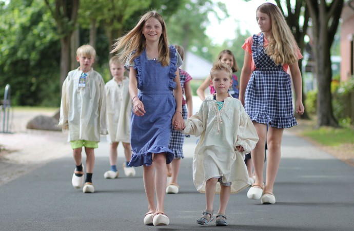 Mehrere Kinder in historischer Kleidung laufen über eine Straße.