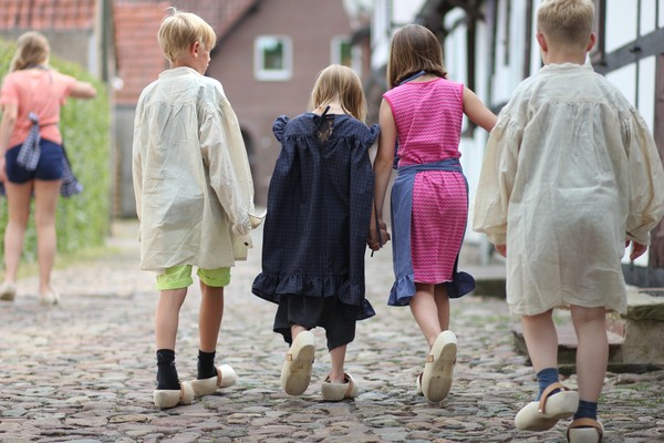 Kinder in historischen Kostümen vor einem Arbeiterhaus.