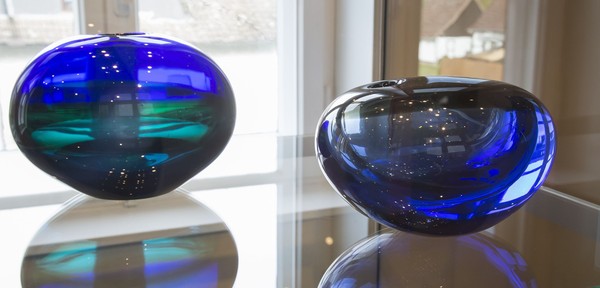 Zwei blaue Glasvasen in einer Vitrine.