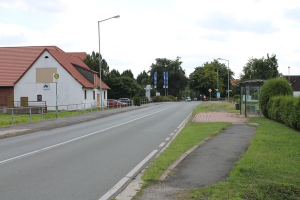 Eine Straße trennt die Parkplätze und eine Bushaltestelle vom Museumsgelände.