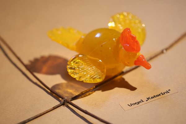 Gelber Glasvogel mit Namensschild "Katerini"