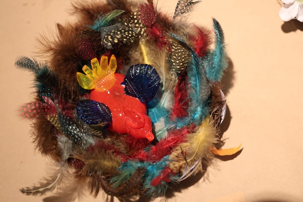 Bunter Glasvogel in mit bunten Federn ausgekleidetem Nest